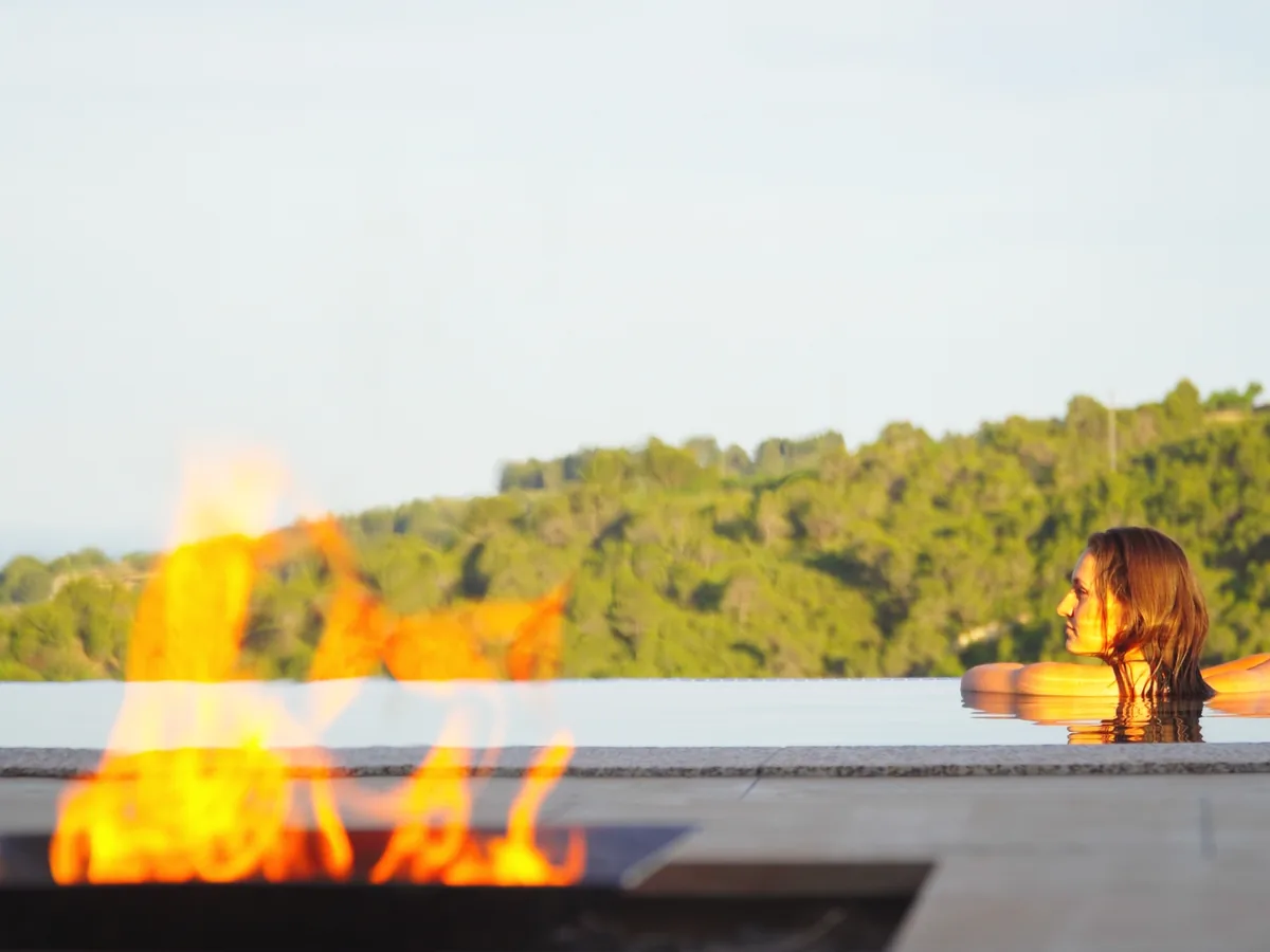 Infinity-Pool mit Feuerstelle im Abendlicht
